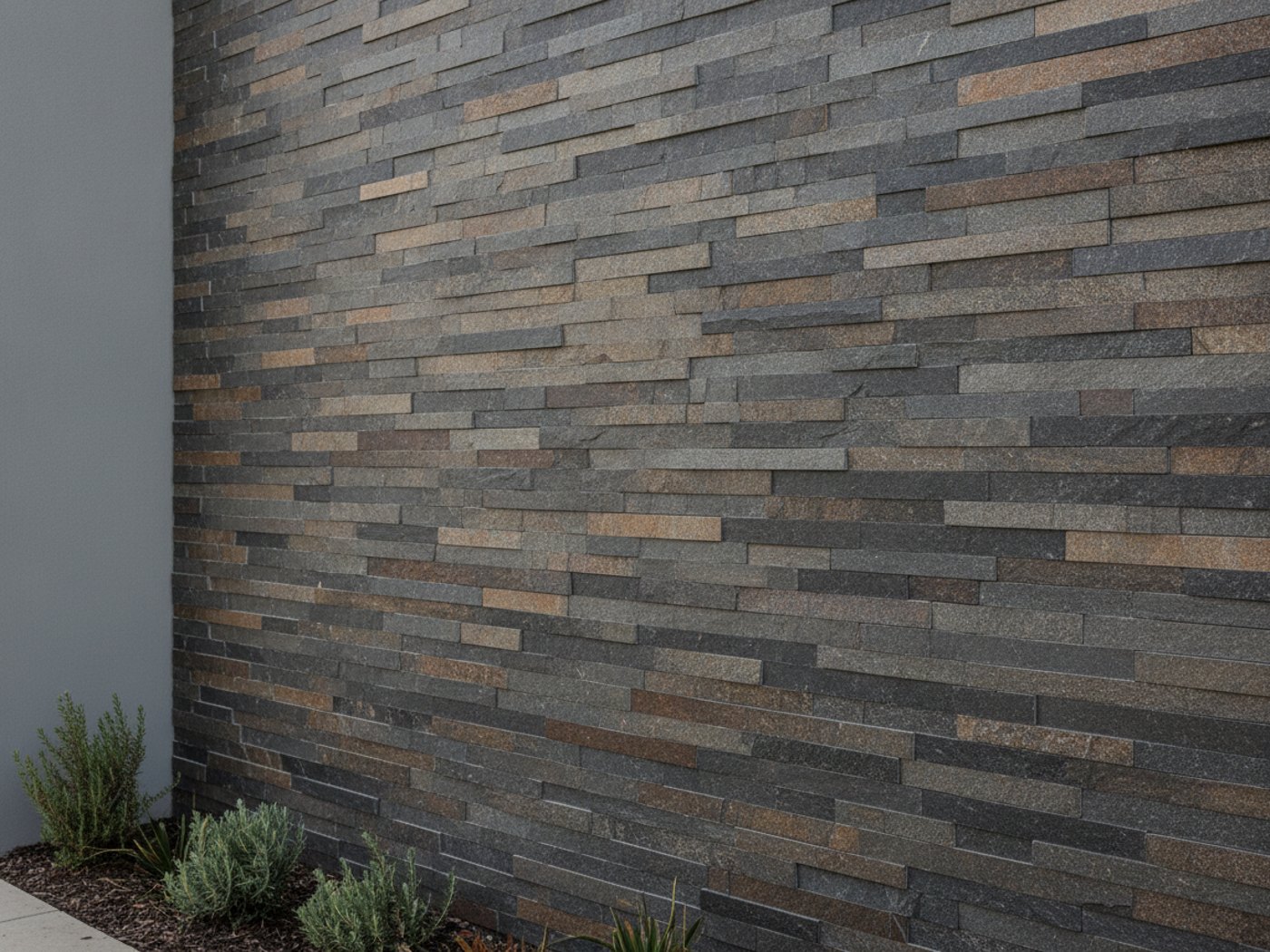 A stacked stone feature wall in warm grey and charcoal tones on a modern home exterior