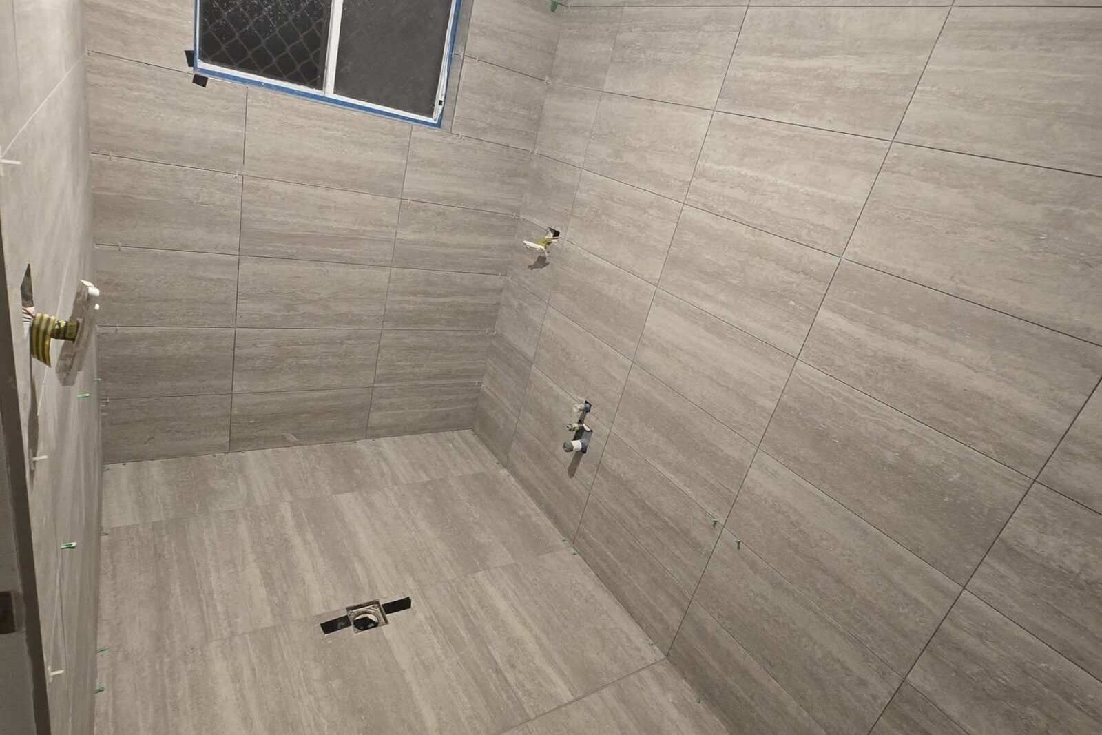 Finished bathroom with colour-matched grout and silicone edging by SLJ Express Tiling