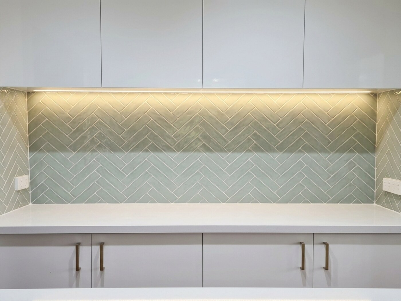 A sage green herringbone tiled splashback finished by SLJ Express Tiling & Waterproofing