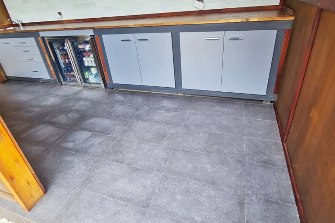 Outdoor kitchen bar tiled by SLJ Express Tiling with 300x600 floor tiles, charcoal grout and a 76x302 subway tile splashback
